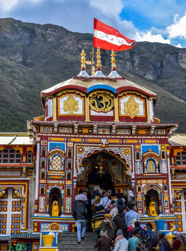 Vibrant view of Shree Badrinath Temple with pilgrims gathered around, set against a mountainous backdrop.